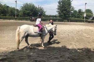 Camper riding horse with counselor